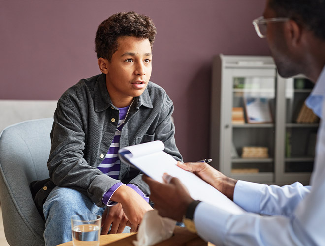 teen boy sitting with clinician understanding adolescent vs adult mental health treatment