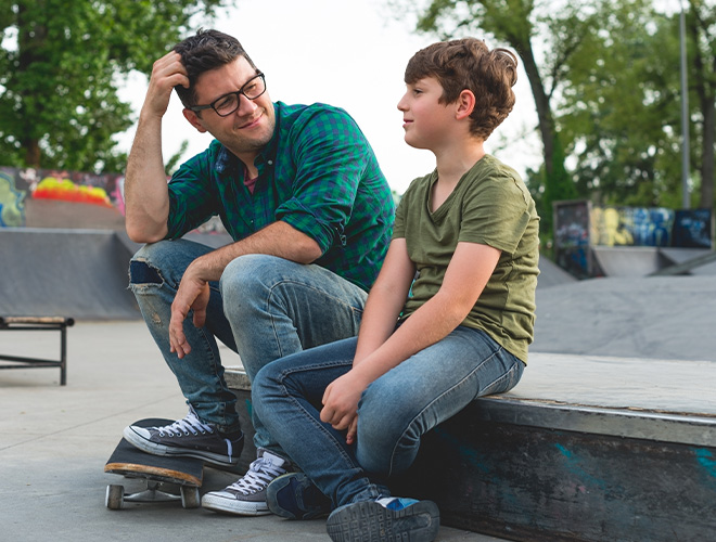 dad talking to his son about anxiety in a neutral setting at the skatepark