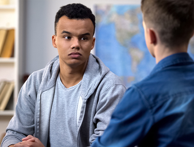 angry teen showing signs of teen rage while speaking to a counselor