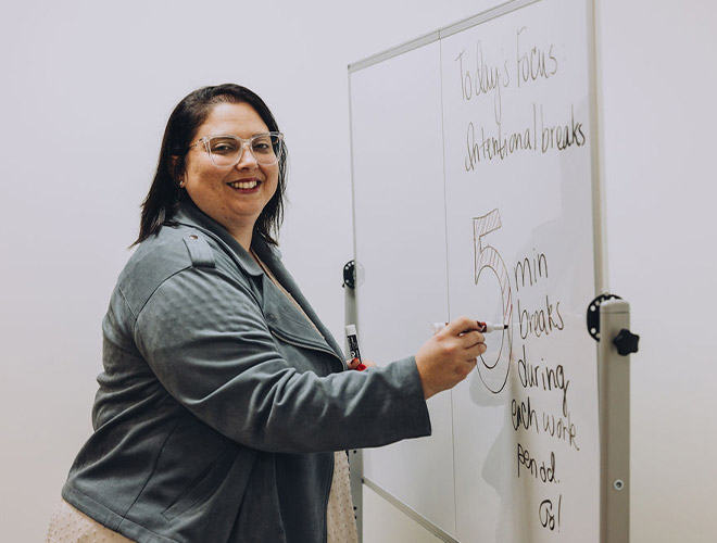 Samantha Canuel, M.Ed., writing on a whiteboard about intentional breaks during a lesson at HavenRise Academy