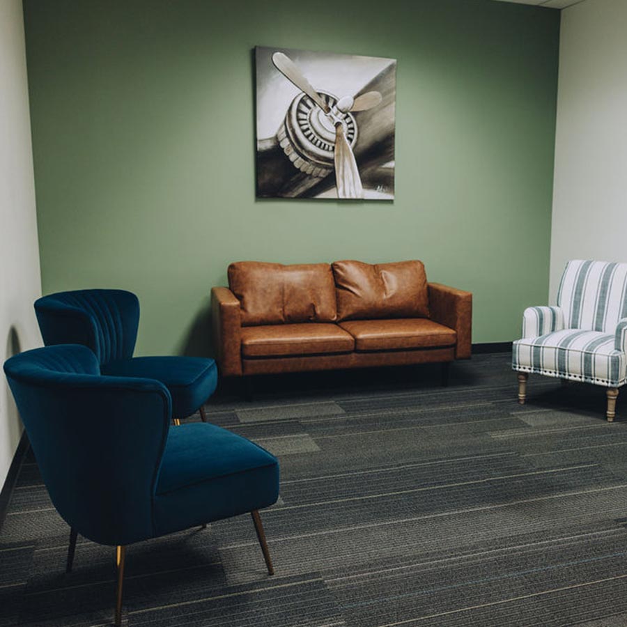 Welcoming therapy room at HavenRise Academy with sage-green wall and soft seating, where Orange Park families meet with the care team.