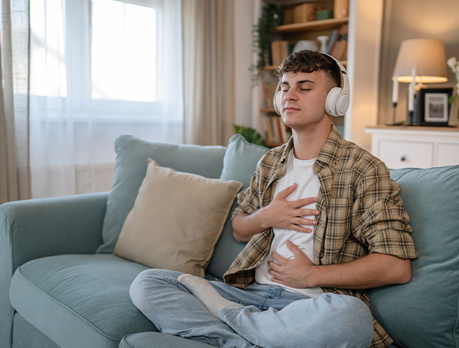 Teen sitting on a couch listening to headphones practicing Wise Mind and Mindfulness