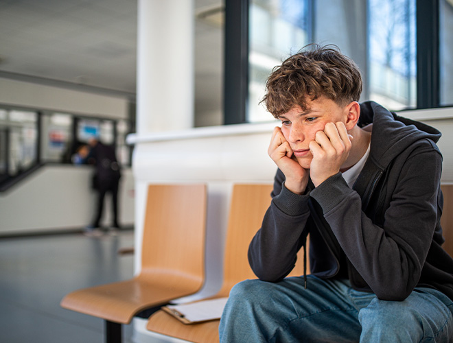 young teen showing signs of social anxiety while sitting on a bench in a public place